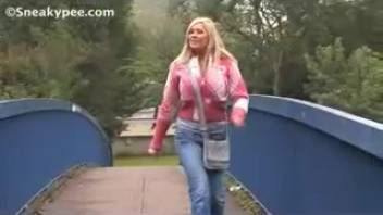 Young woman in rose coat urinating on the overpass